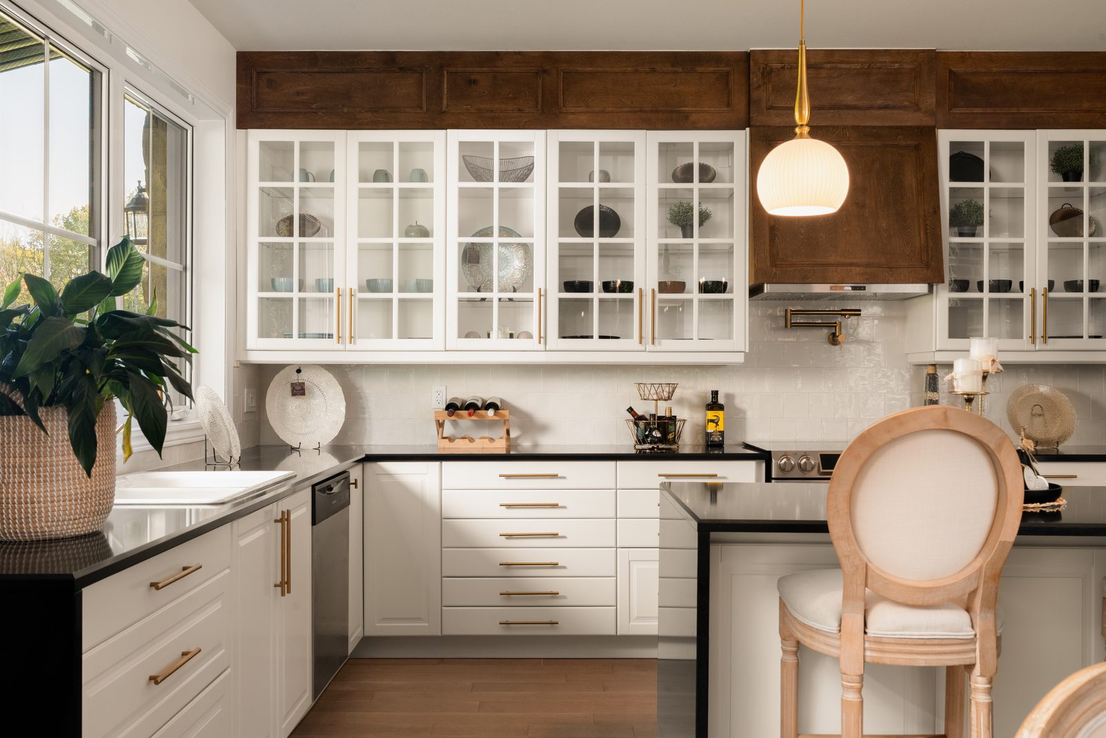 Cuisine aux armoires vitrées, suspension globe et chaise capitonnée, en lumière douce