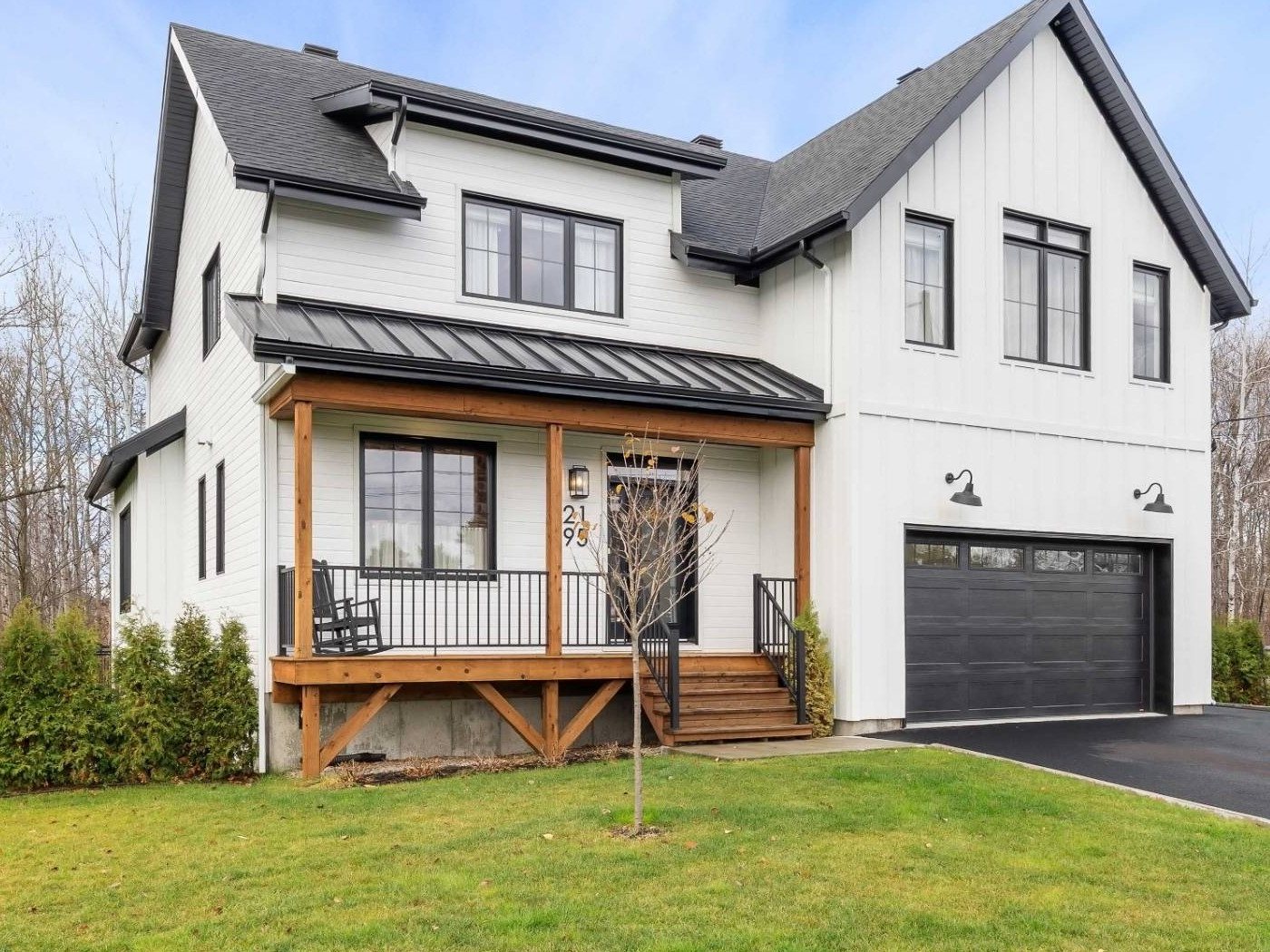 Façade d'une maison de style farmhouse blanche, porche de bois et garage double