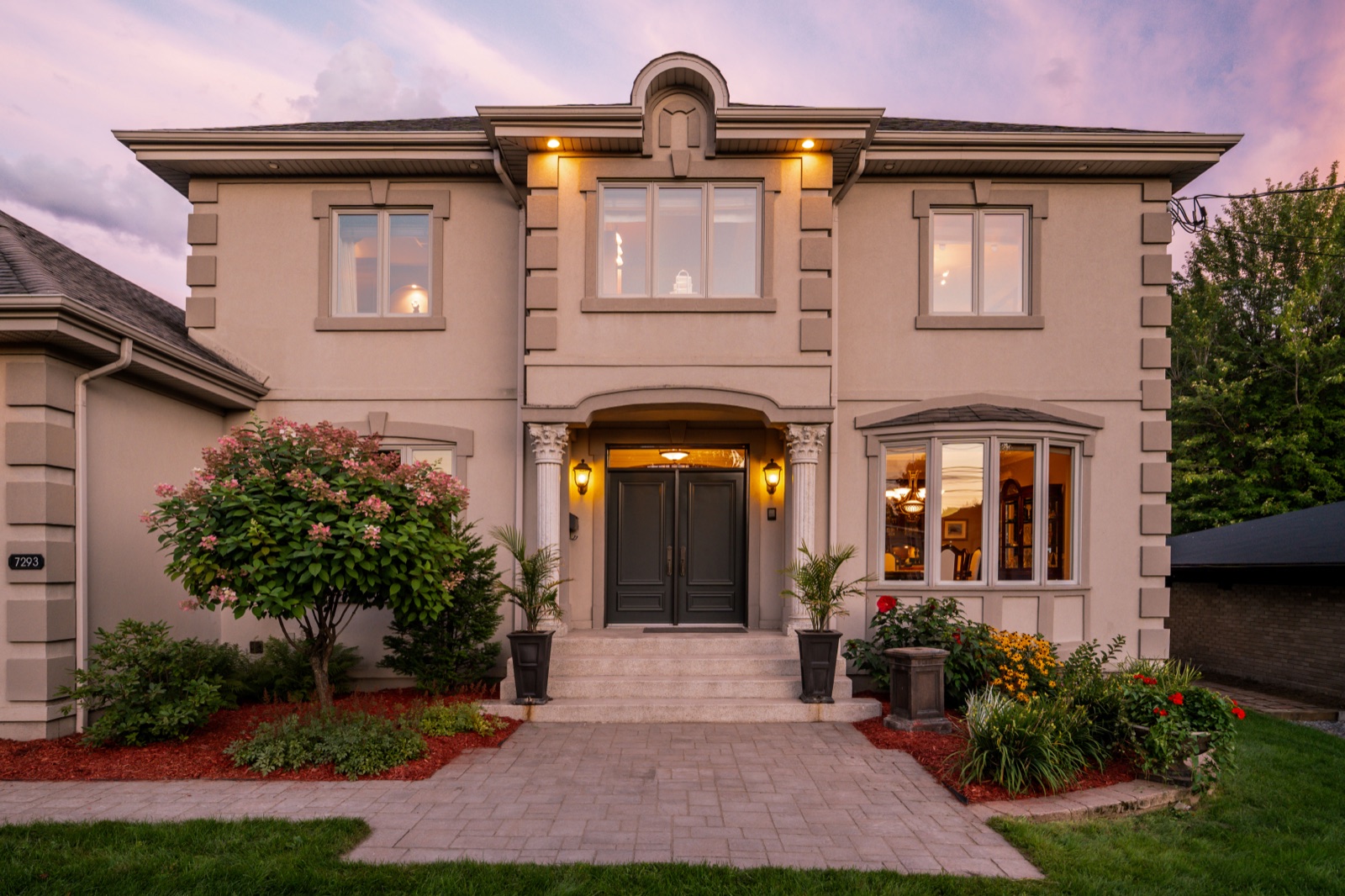Façade du 7293 Rue du Pont au crépuscule, colonnes et portes noires sous le ciel rose