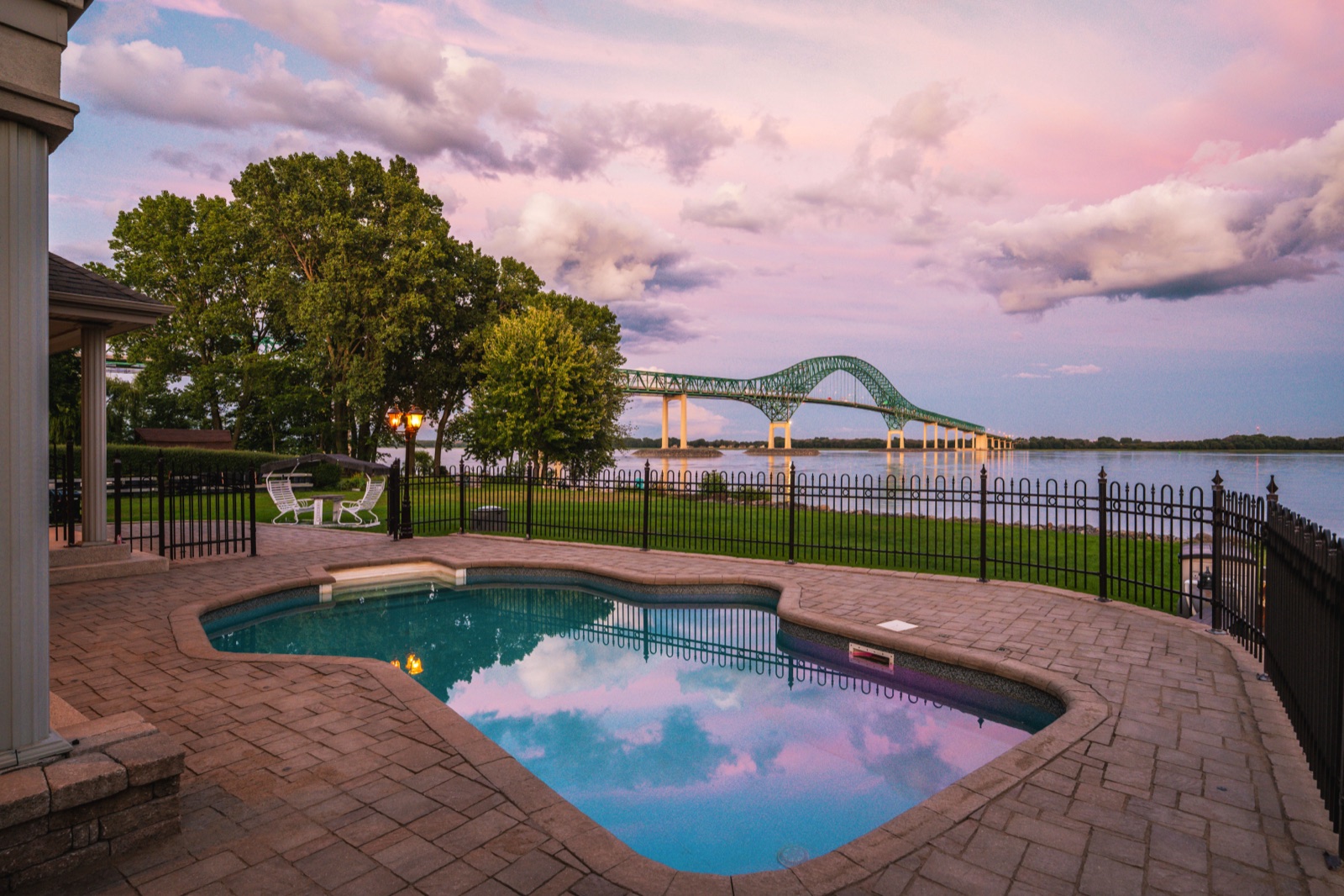 Piscine au crépuscule, ciel rose reflété dans l'eau et pont Laviolette au loin