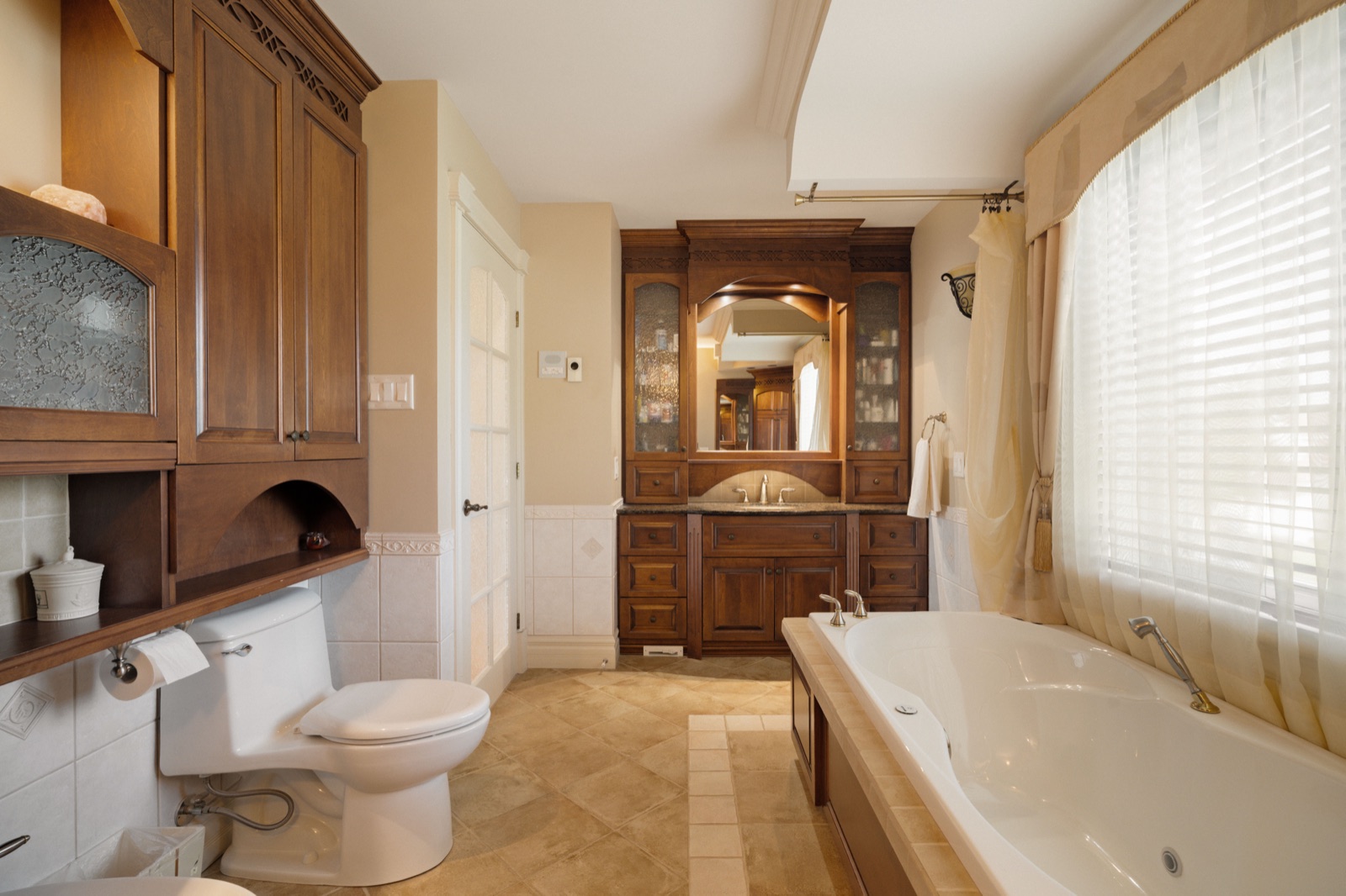 Salle de bain aux boiseries de merisier, baignoire sous la fenêtre voilée