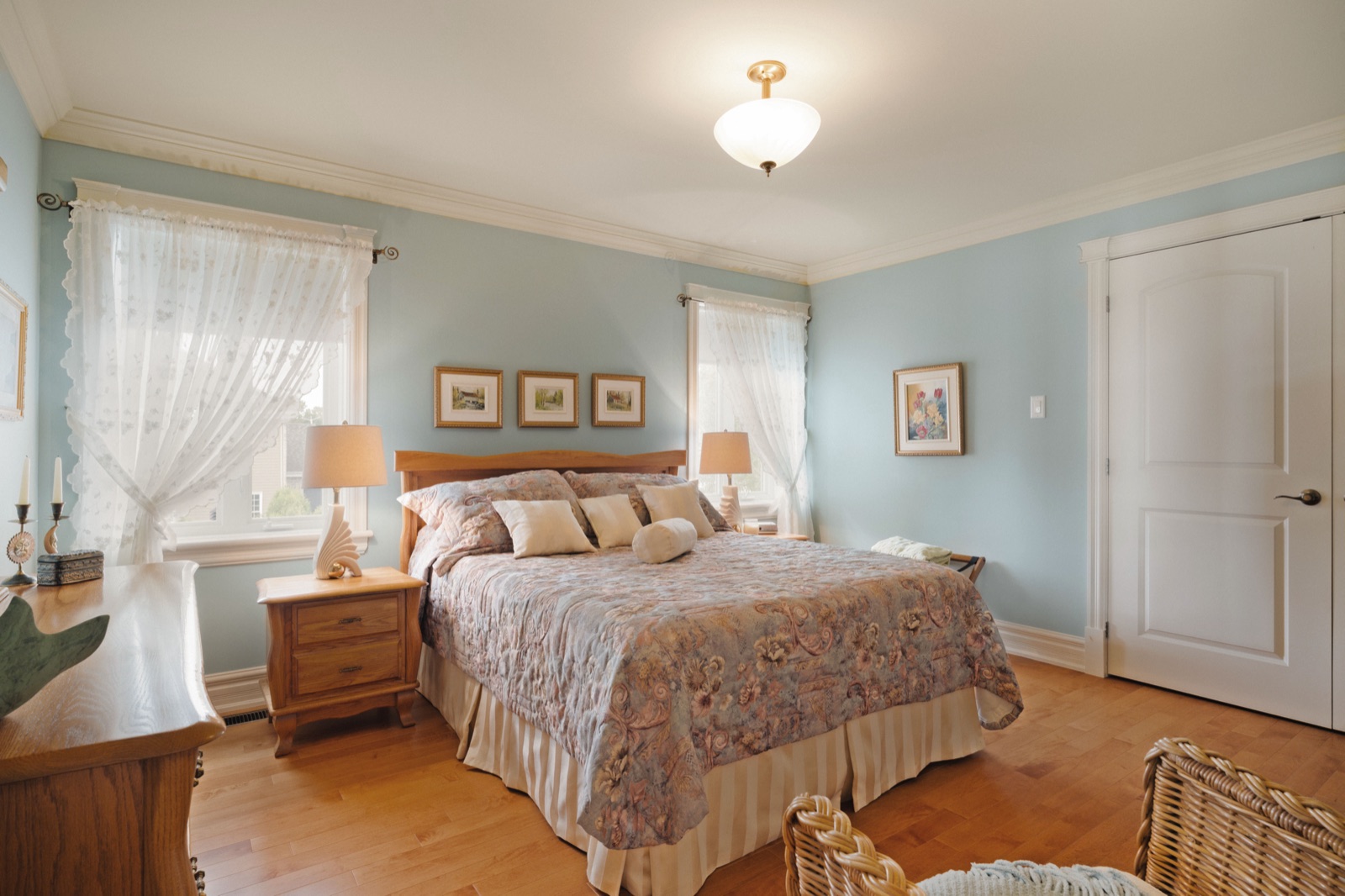 Chambre bleu ciel avec lit de bois et rideaux de dentelle