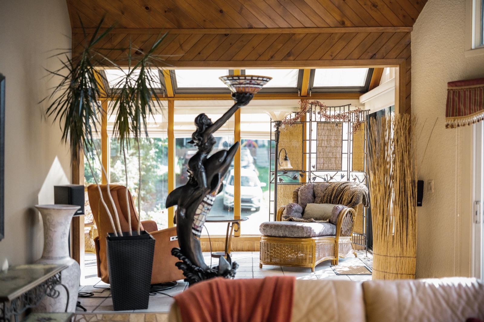 Passage du séjour vers le solarium, fauteuils de rotin baignés de lumière